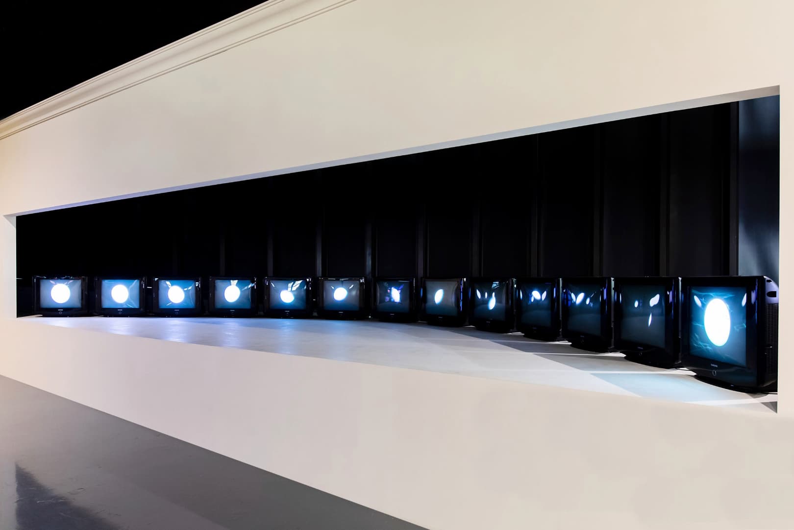 Nam June Paik, Moon is the Oldest TV (1965). Twelve CRTs, each deflected by magnets into a moon phase.